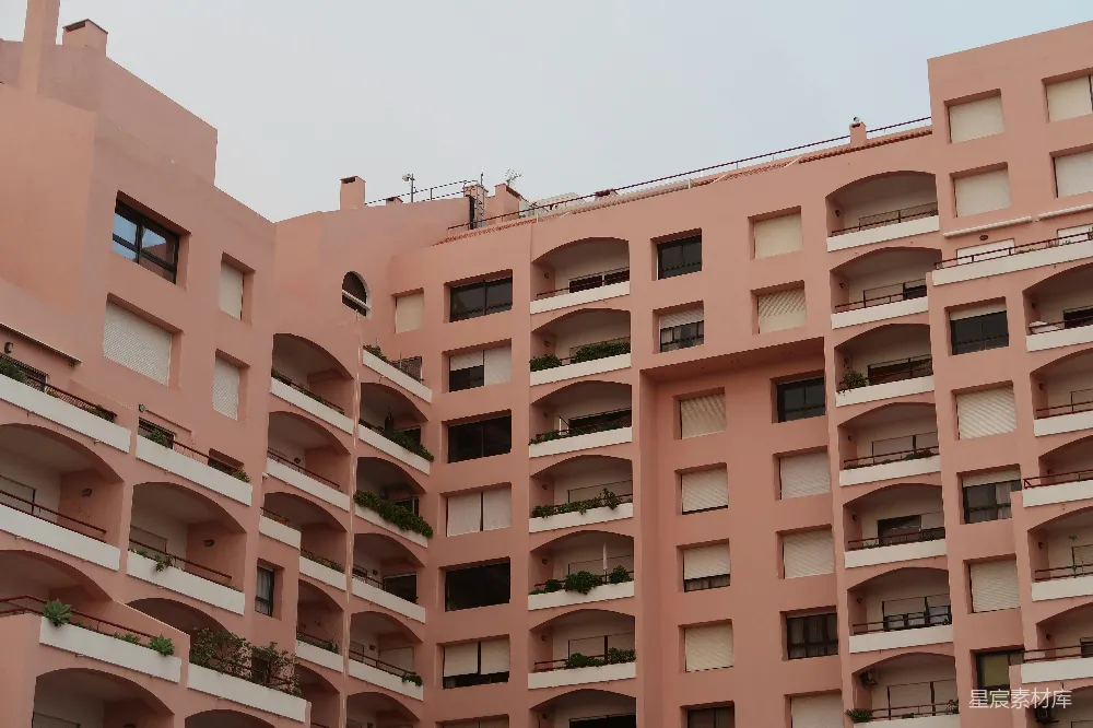 高清摄影  一座大型粉红色建筑，有许多拱形窗户和阳台。