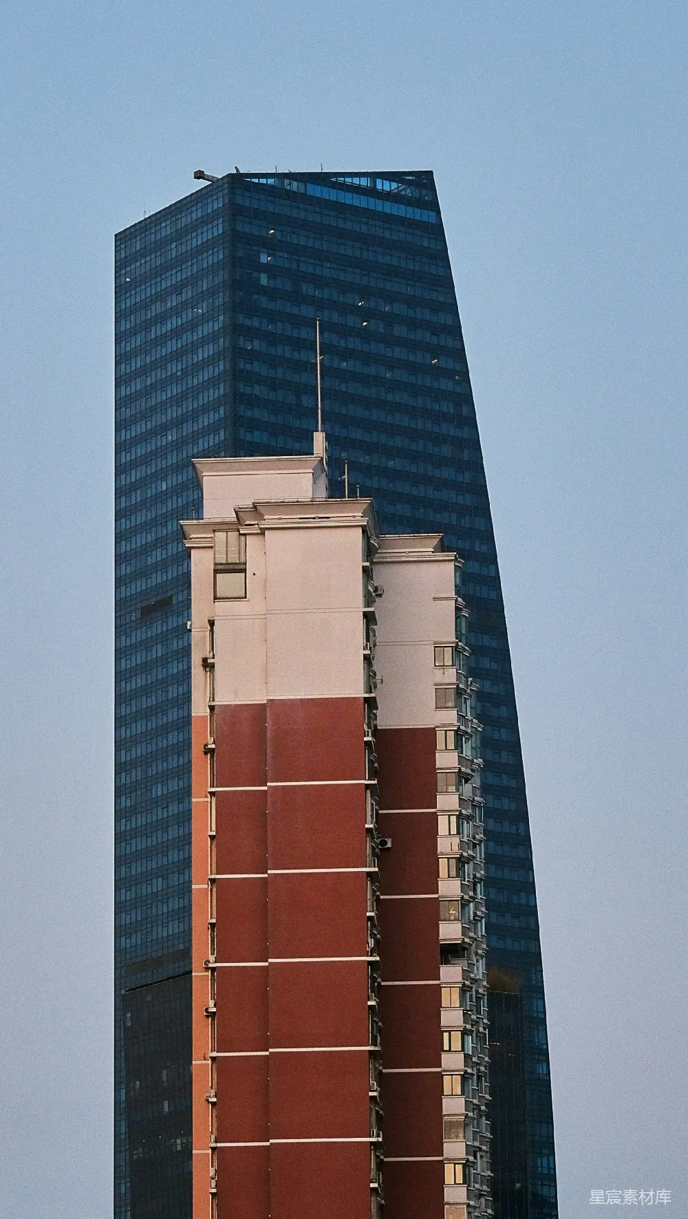 高清摄影  现代玻璃摩天大楼位于一座较旧的住宅建筑后面。