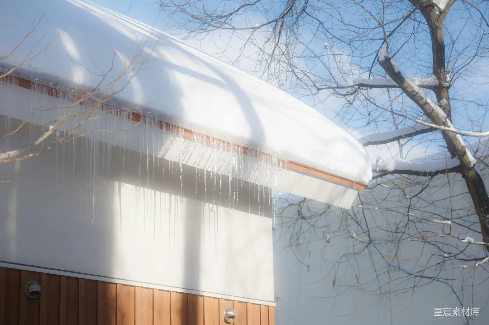 高清摄影  冰锥从覆盖着雪的屋顶垂下