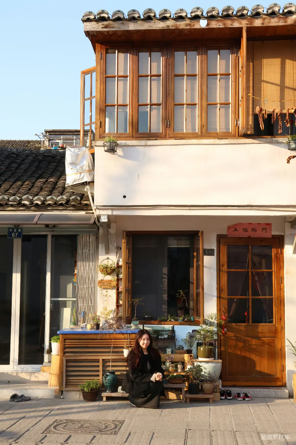 高清摄影  一位女士坐在一座迷人的、木制边框建筑物外面。
