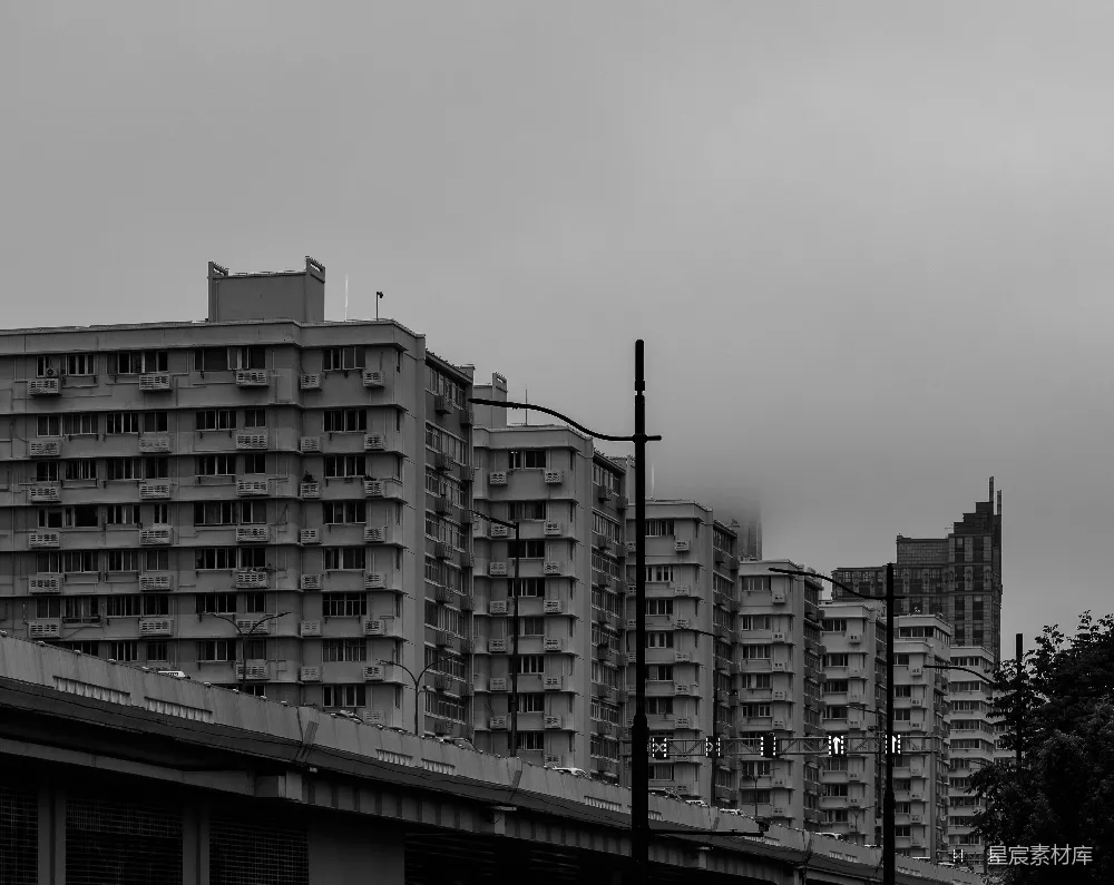 高清摄影  一排高耸的公寓大楼在阴云密布的单色天空下。
