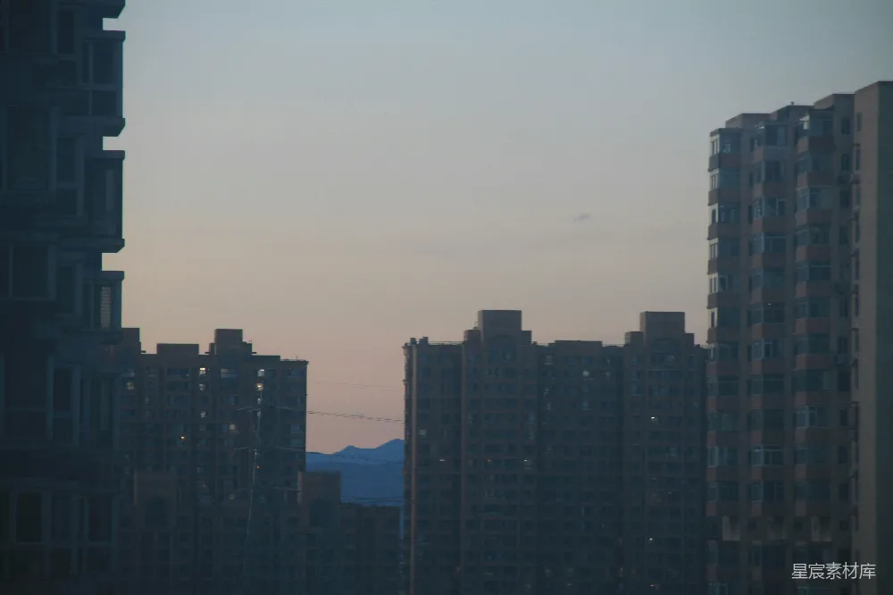 高清摄影  在暮色天空下，高耸的建筑剪影与远处的山脉相映成趣。