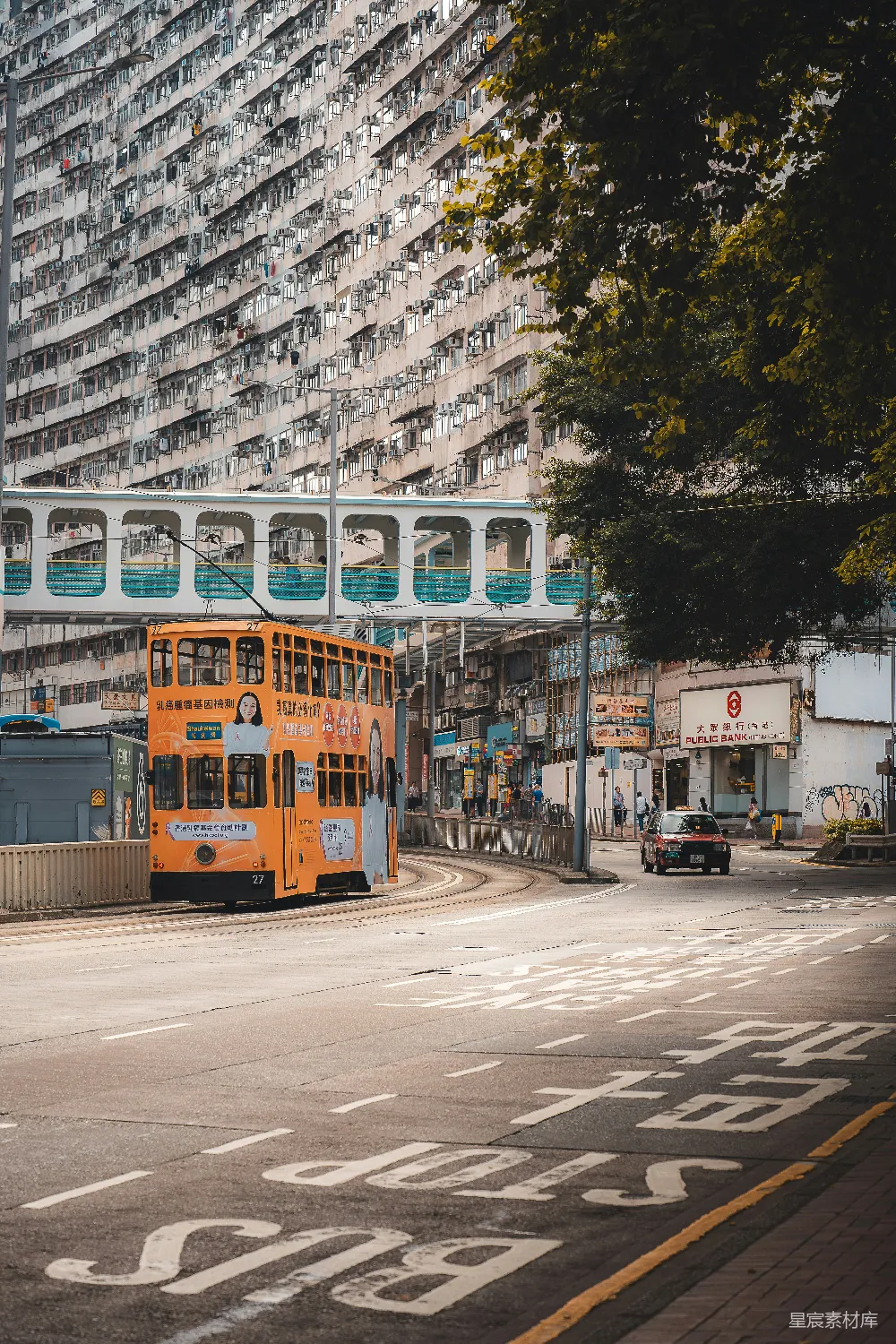高清摄影  橙色的有轨电车行驶在街道上，两旁是建筑物和树木。