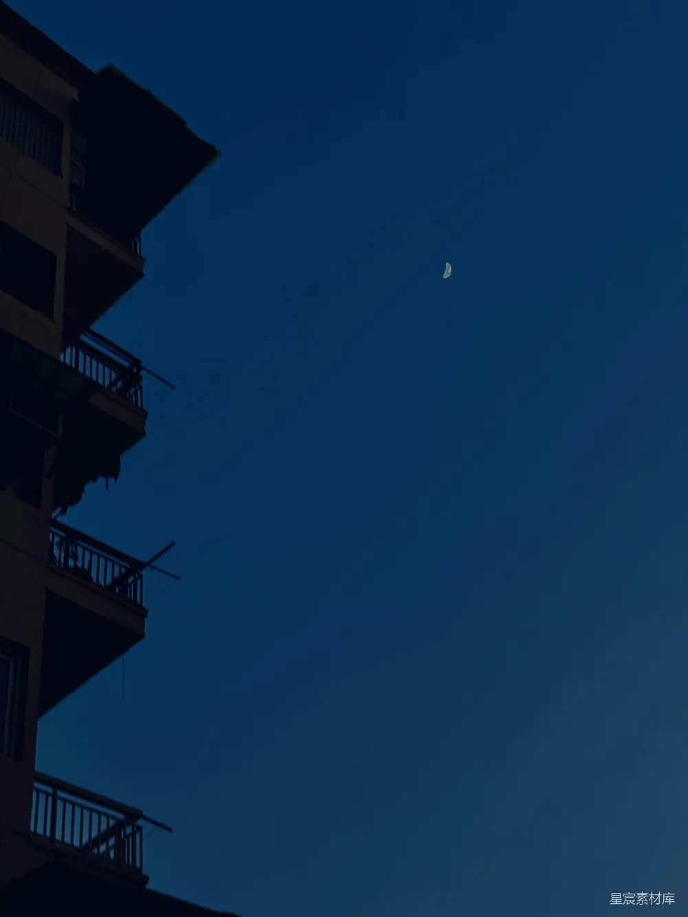高清摄影  剪影建筑在深蓝色的天空中，月亮呈现出新月形状。