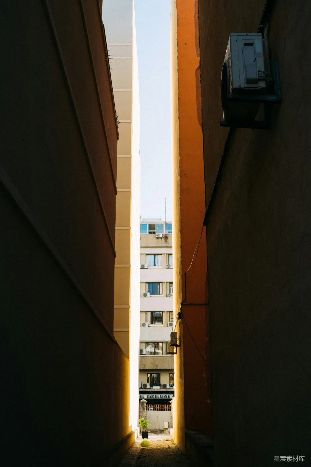高清摄影  建筑物之间的狭窄巷道，远处可见城市景色。