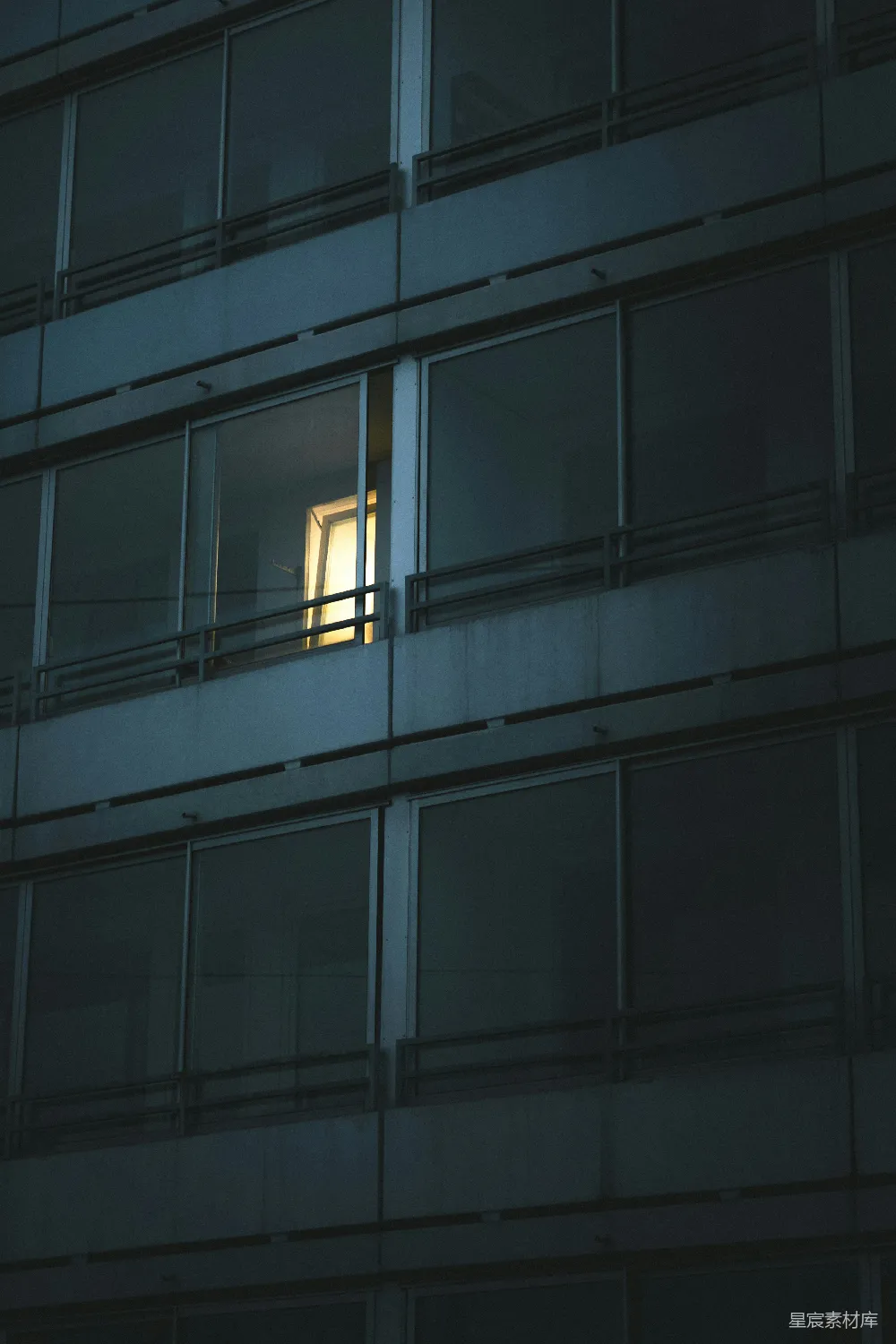 高清摄影  一栋黑暗建筑外表上一扇亮着灯的窗户。