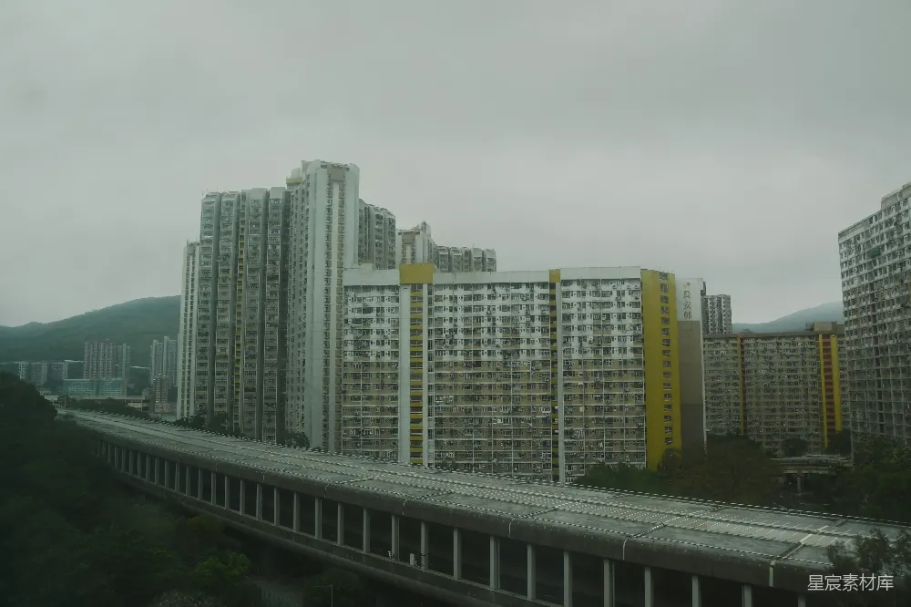 高清摄影  一排高耸的公寓楼沿着山丘排列，紧邻一条铁路。