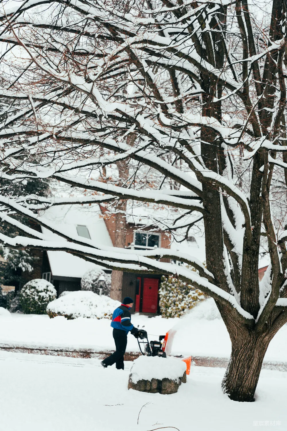 高清摄影  男人在房子前用扫雪机清理积雪。