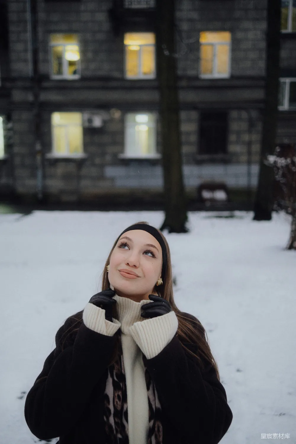 高清摄影  年轻的女子在黄昏时分的雪地庭院中抬头看。