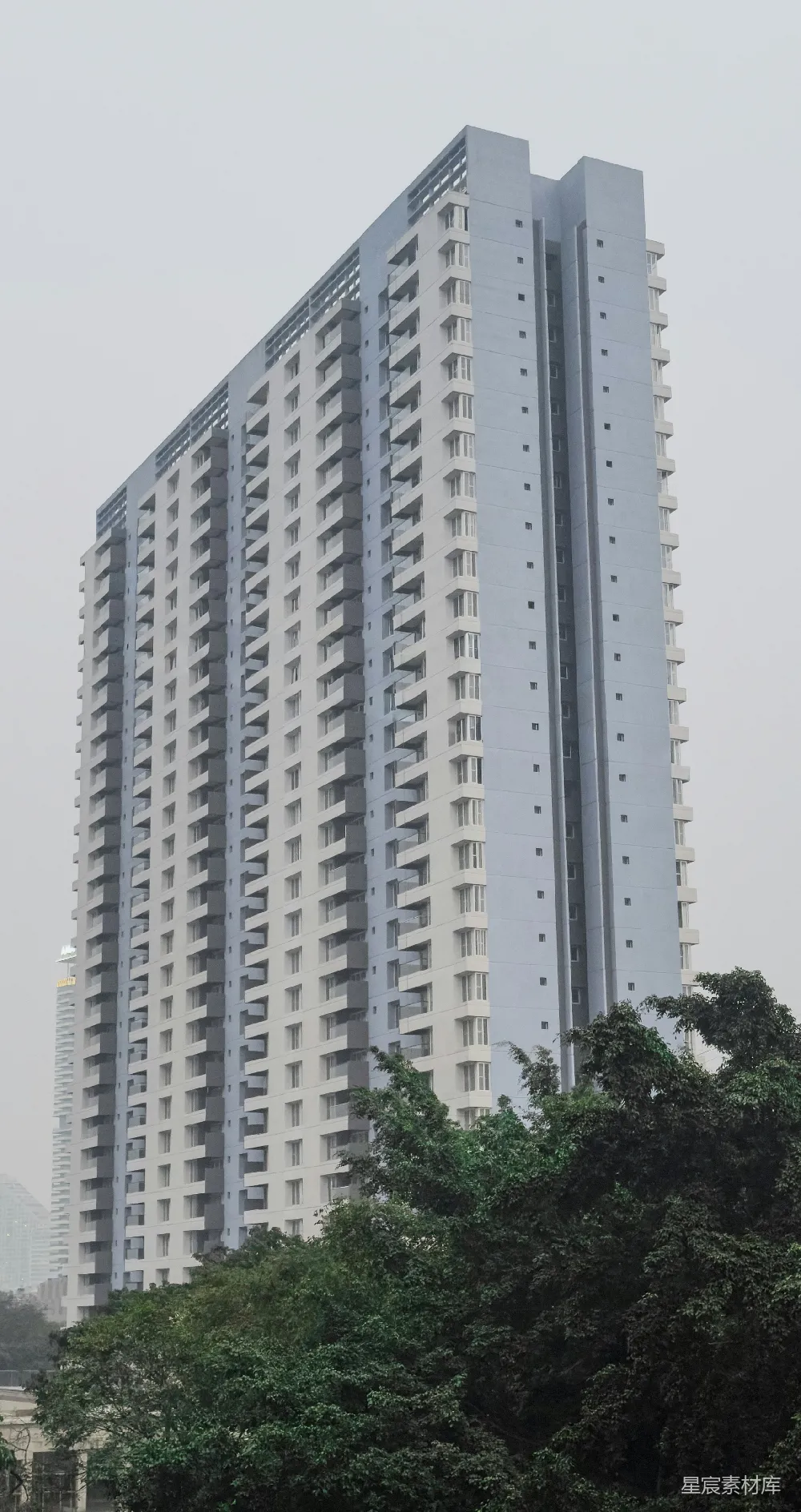 高清摄影  一座有许多阳台的高层公寓楼，背景是朦胧的天空。