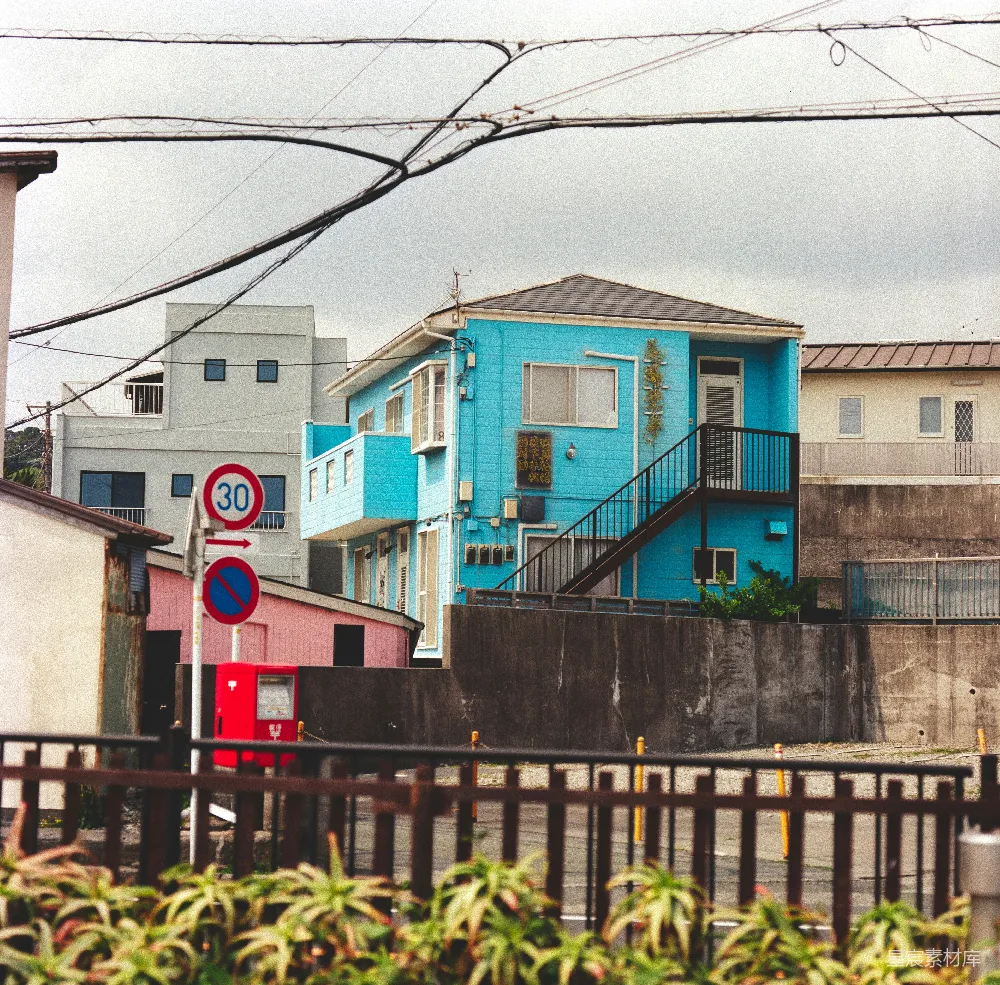 高清摄影  明亮的蓝色建筑，带有楼梯和街道标志。