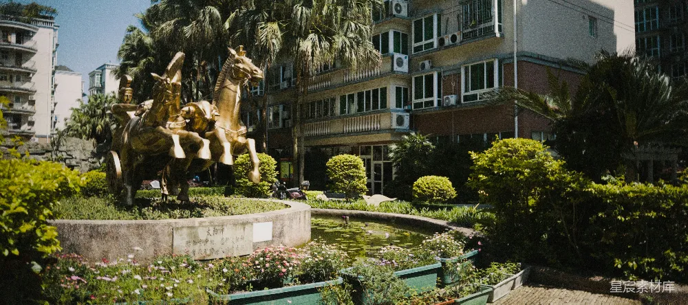 高清摄影  花园中有一座青铜战车雕塑，旁边有一座建筑。