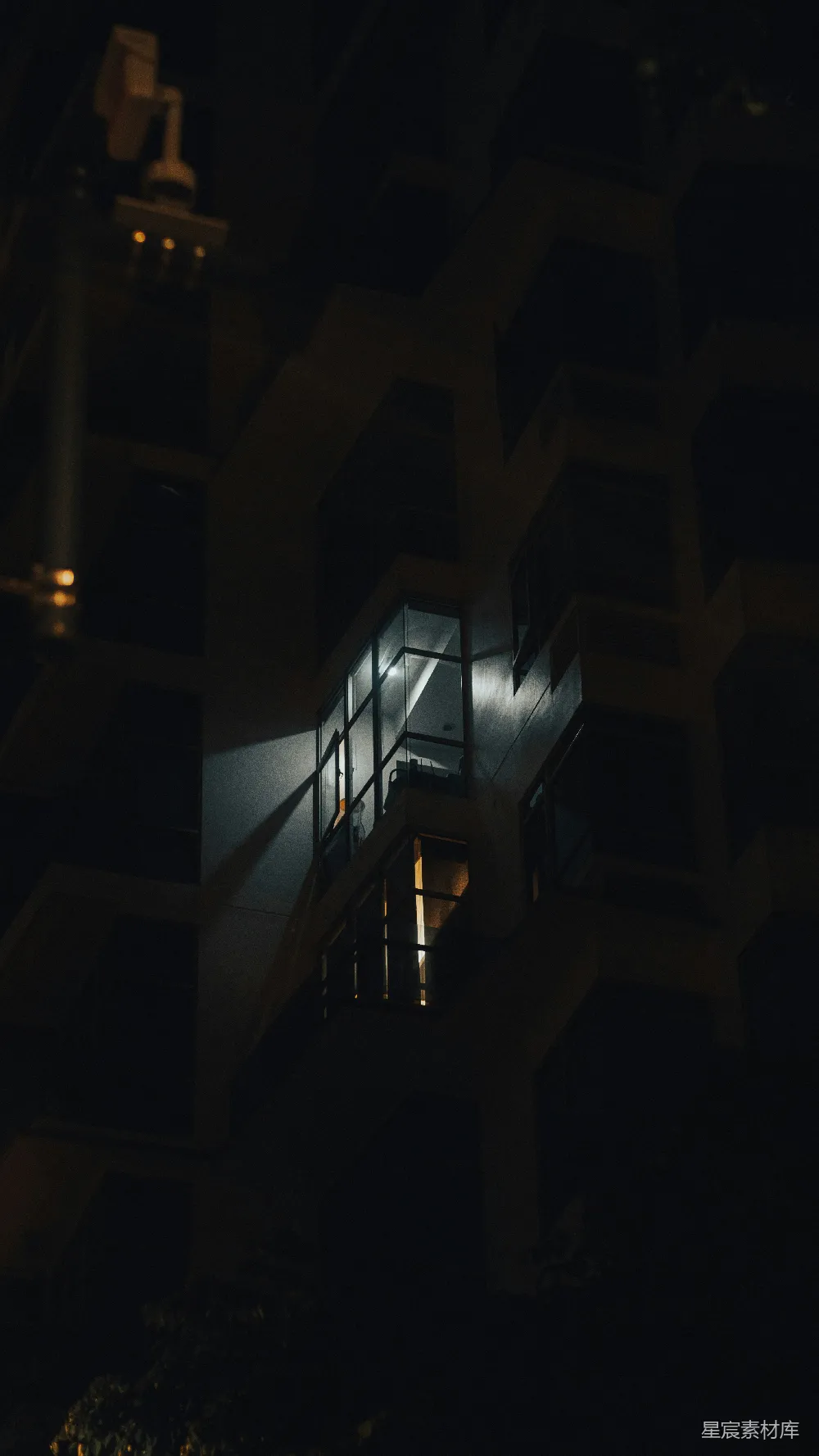 高清摄影  夜晚，一幢黑暗中的建筑里一扇亮着灯的窗户。