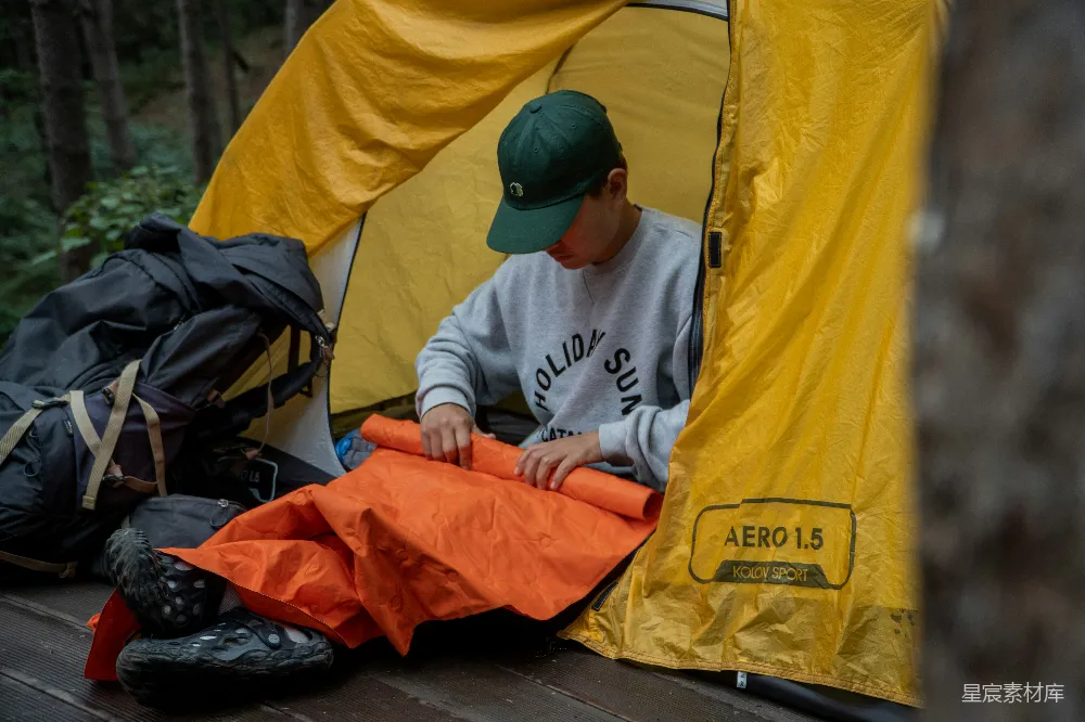 高清摄影  一个男人坐在帐篷里，旁边放着一个睡袋。