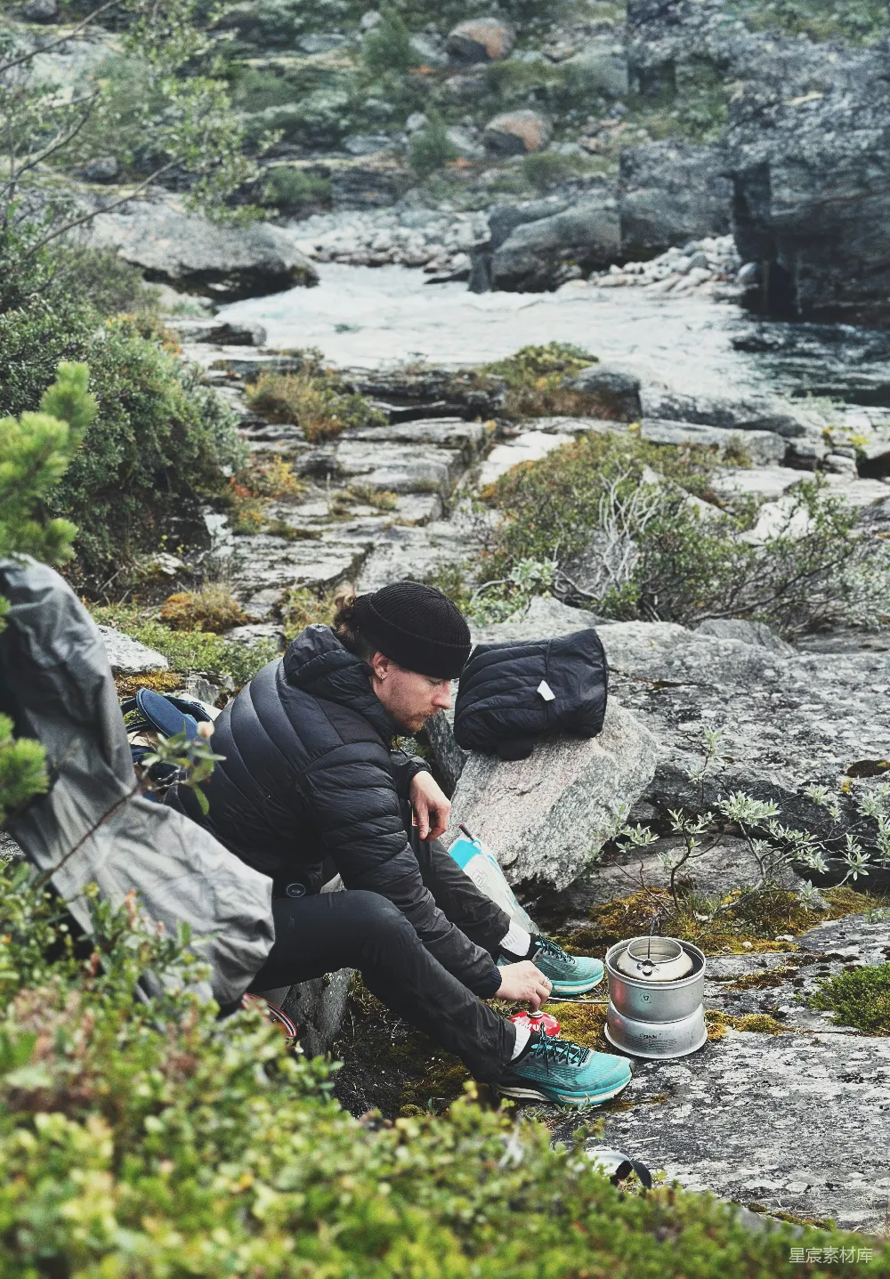高清摄影  一个男人坐在河边的岩石上。