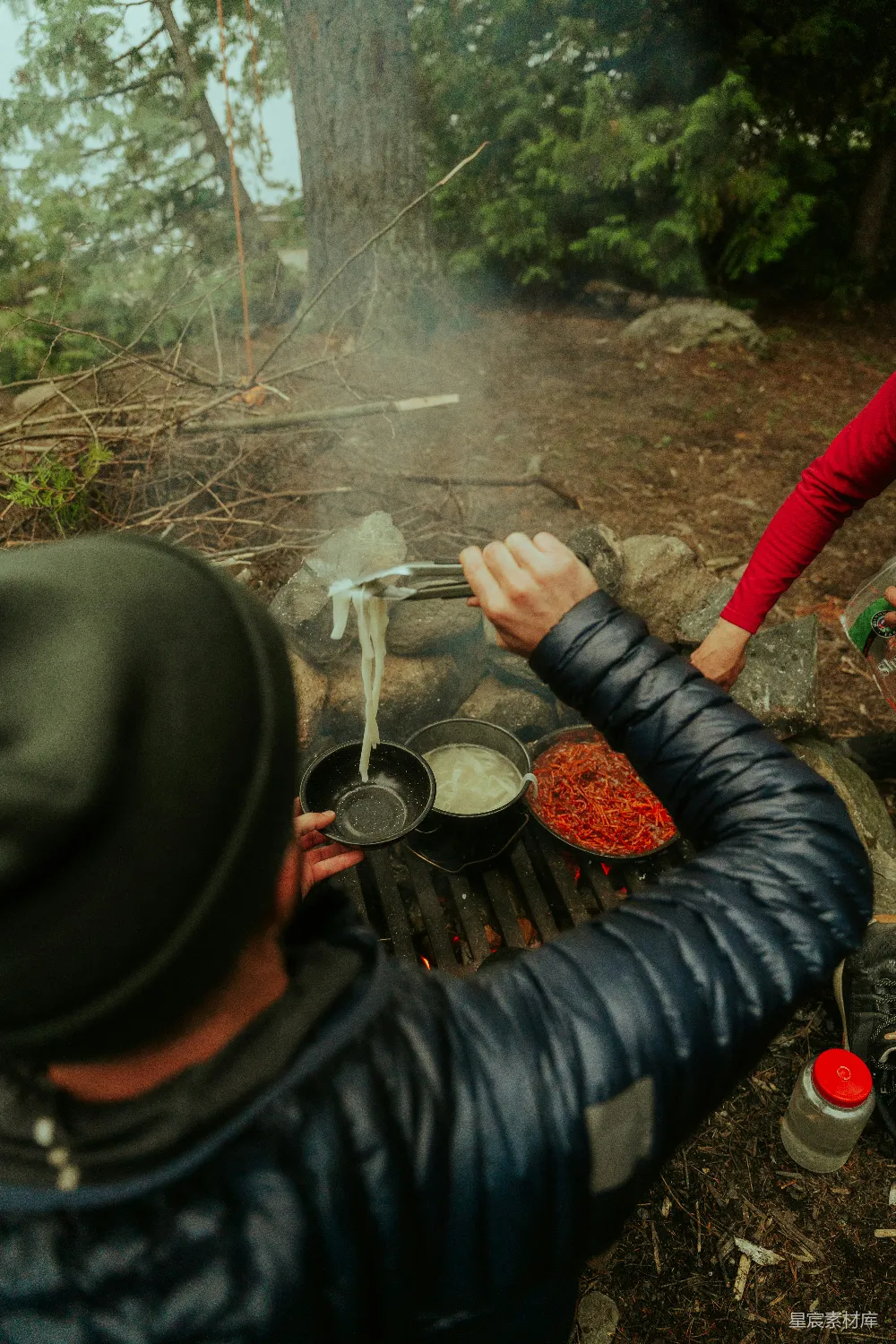 高清摄影  一个男人和一个女人在篝火旁做饭。
