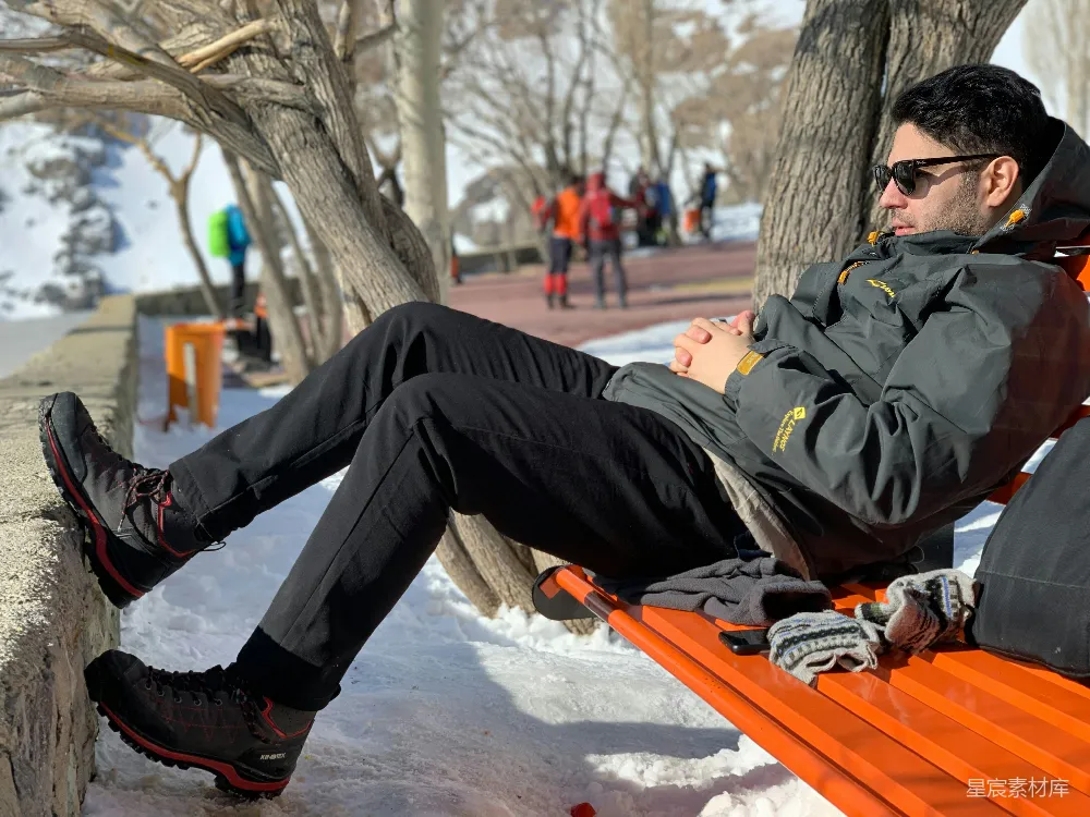 高清摄影  戴墨镜的男人穿着冬装，在雪地上休息。
