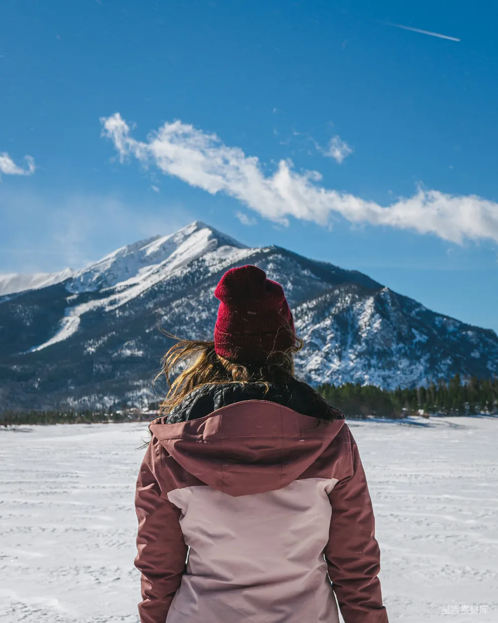 高清摄影  一个女人站在雪地里，背景是一座山。
