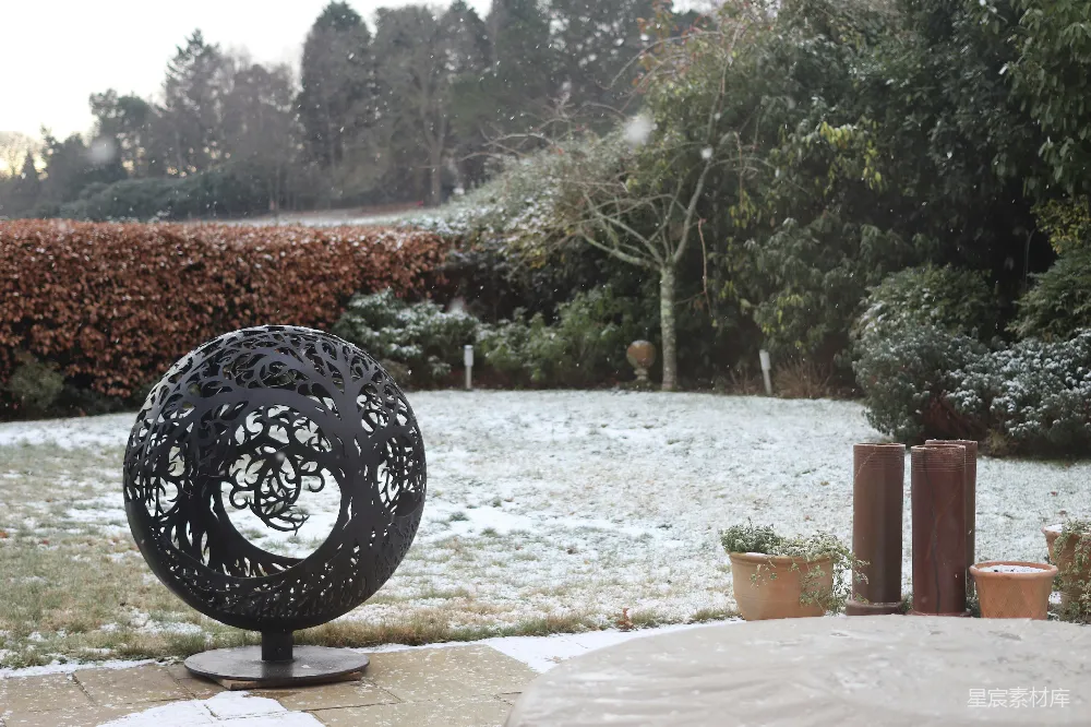 高清摄影  装饰性球形火坑在雪地花园环境中。