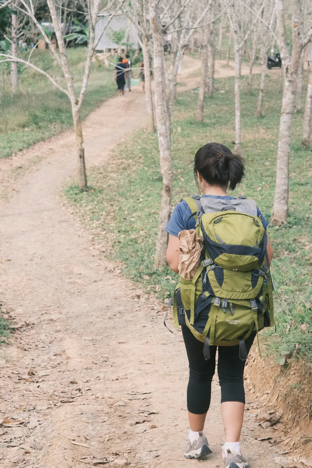 高清摄影 人物 背着背包的女人在泥泞的小路上行走。