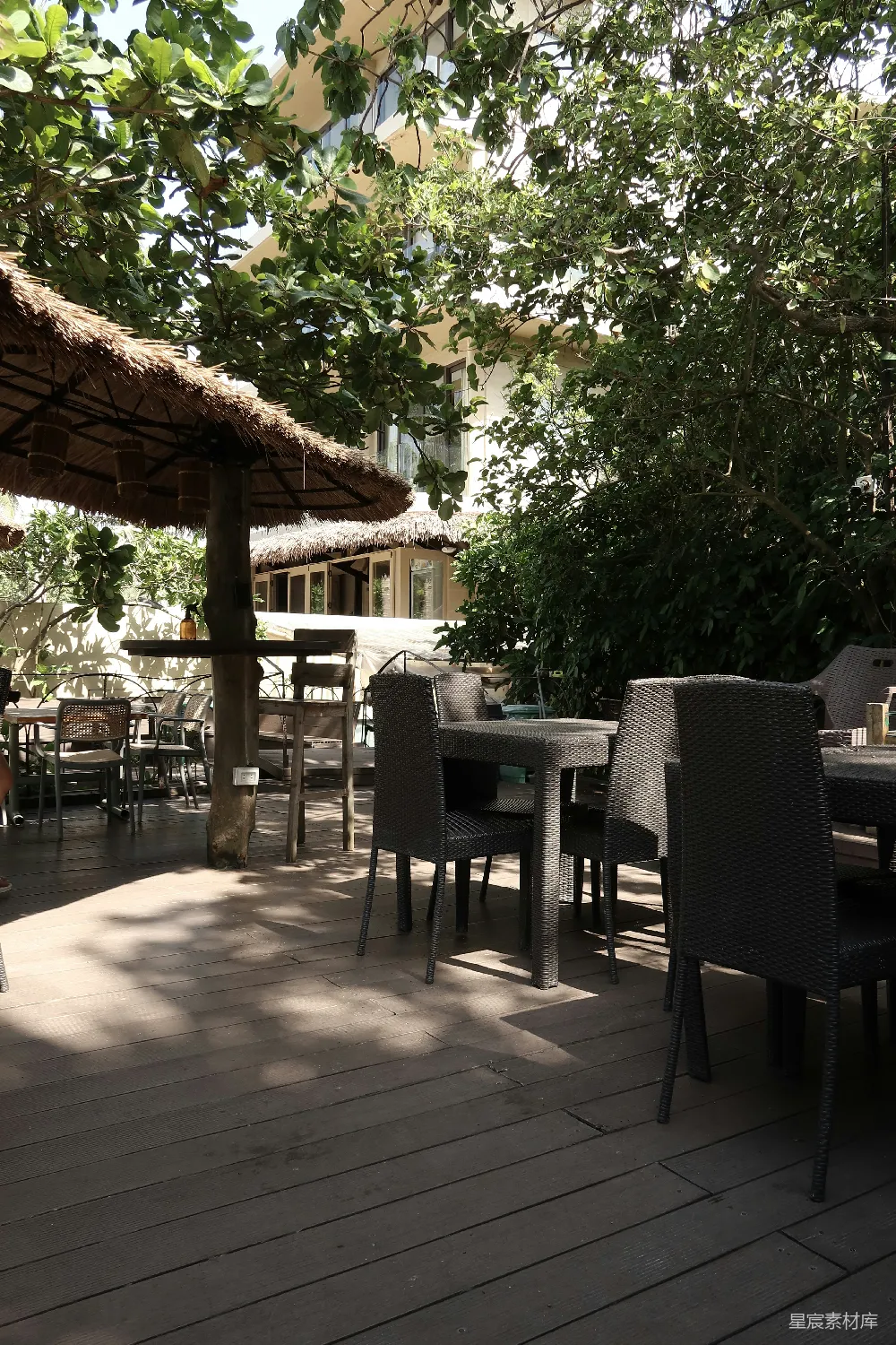 高清摄影  遮阳的户外用餐区，有桌子、椅子和茂盛的树木。