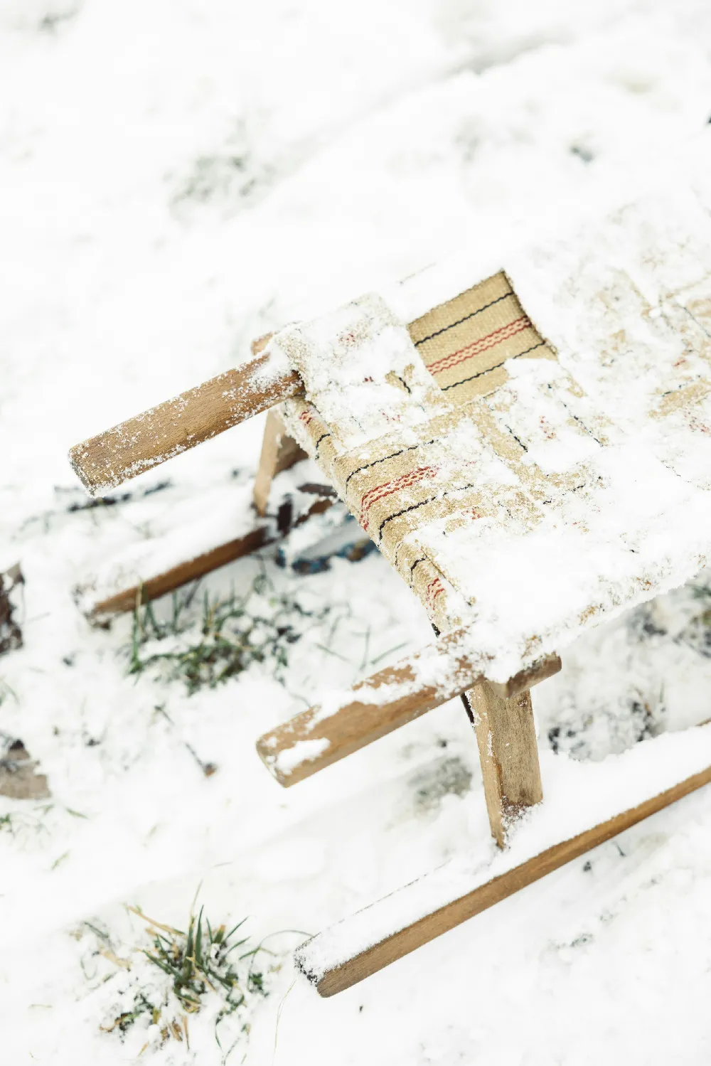 高清摄影  一把木椅坐在积雪覆盖的地面上。