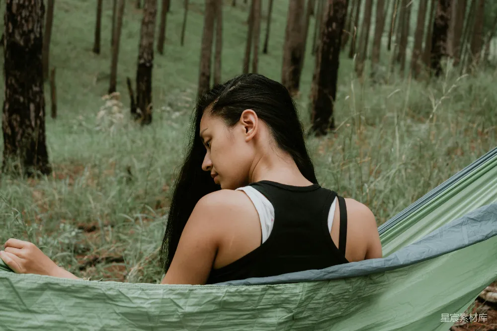 高清摄影  穿黑色上衣的女人坐在绿色吊床上。