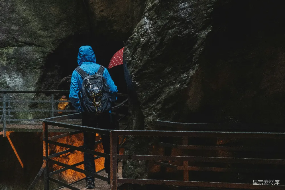 高清摄影  穿蓝色连帽夹克的人站在洞穴附近的桥上。