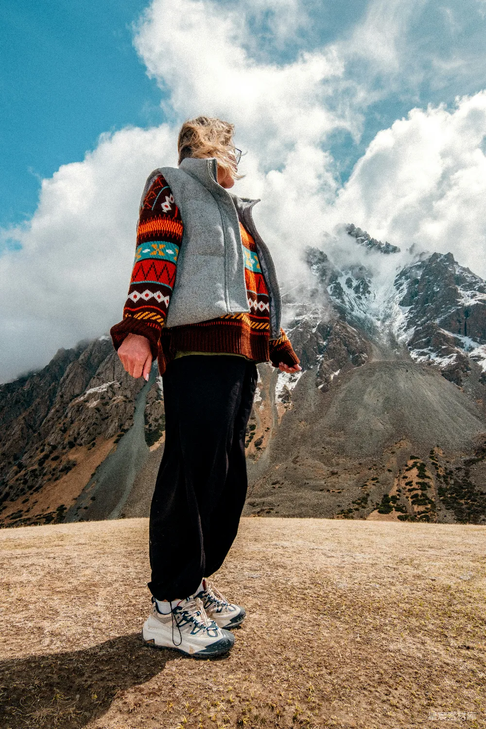 高清摄影 乐观 旅行 人物 穿着五颜六色毛衣的女子站在壮丽的雪山前。