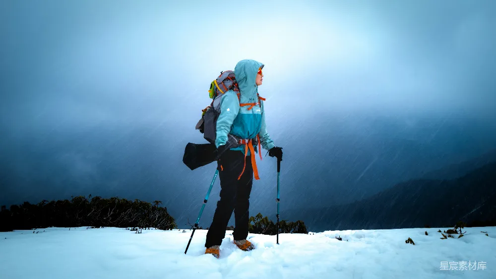 高清摄影 人物 电影 旅行 一名徒步者站在雪地里，背着背包，手拿登山杖。