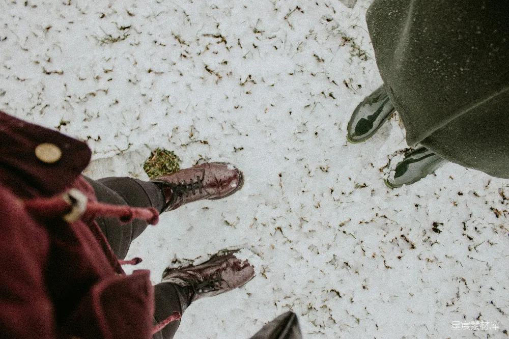 高清摄影  两个人站在雪地里，低头看。