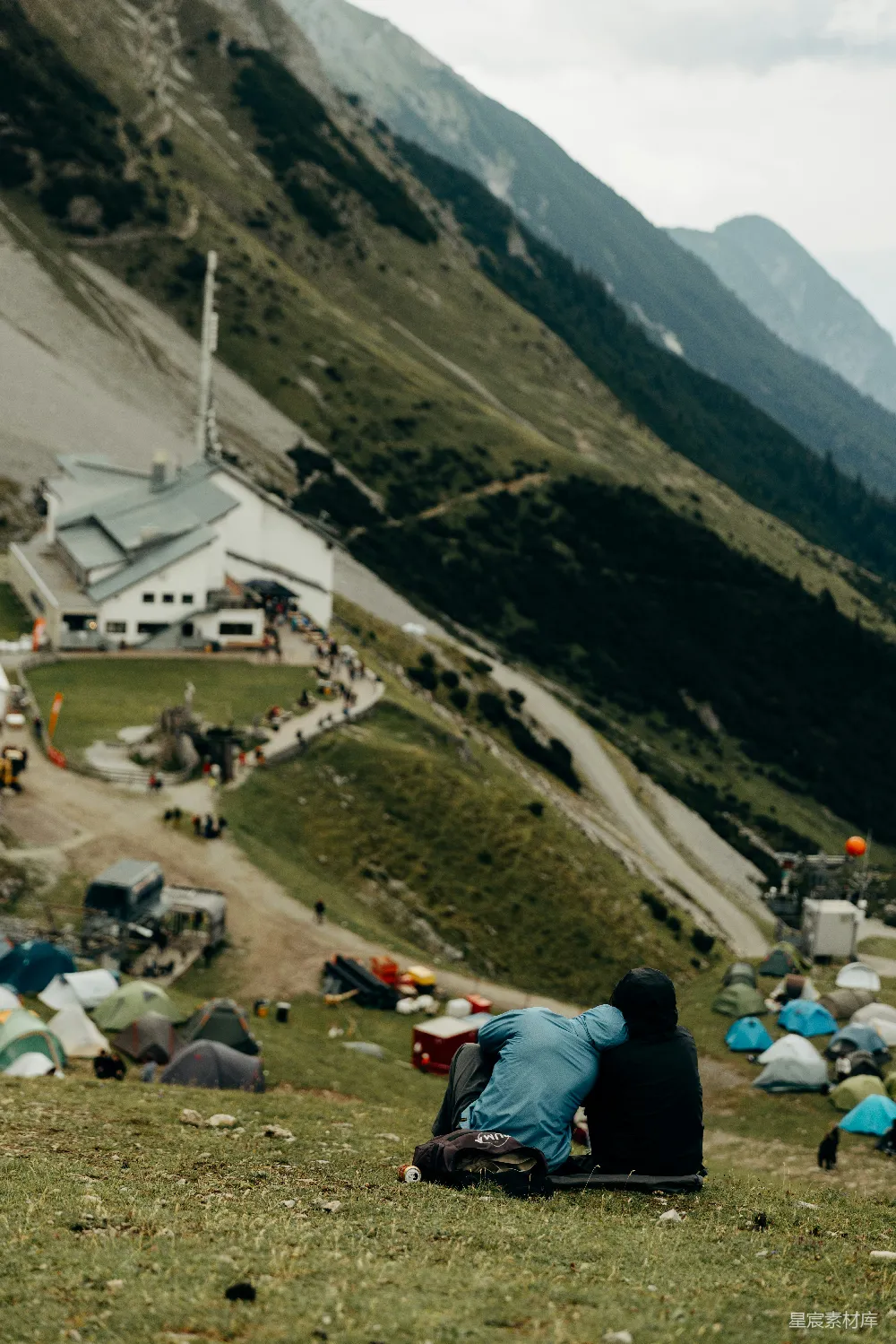 高清摄影  两个人坐在那里，俯瞰着一个山上的营地和小屋。