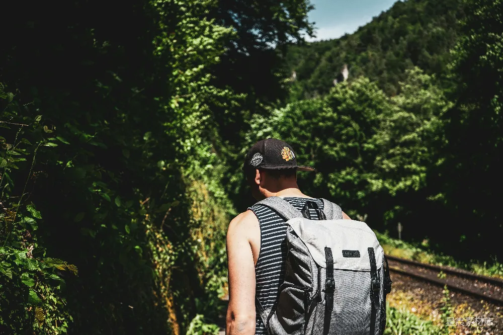 高清摄影  浅景深照片，一个戴着黑色平檐帽、背着灰色背包的男人。