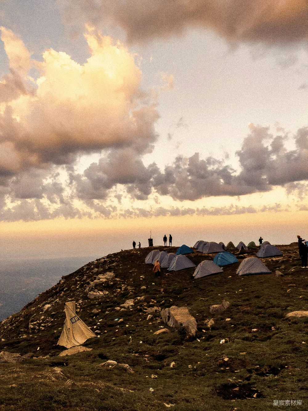 高清摄影  帐篷和人们在山坡上露营，夕阳西下。