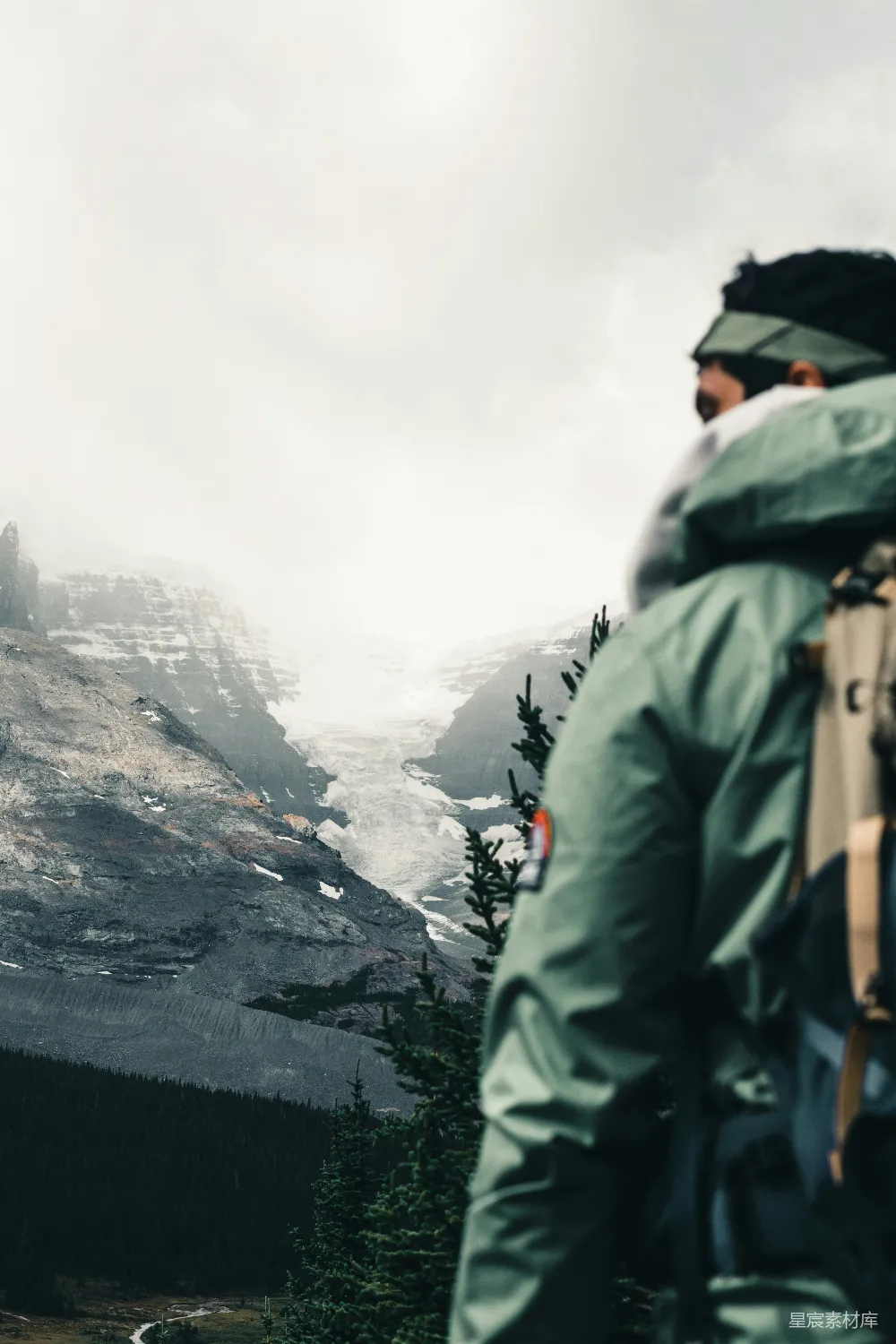 高清摄影  穿着绿色夹克和背着黑色背包的男人站在岩石堆上，白天时分。