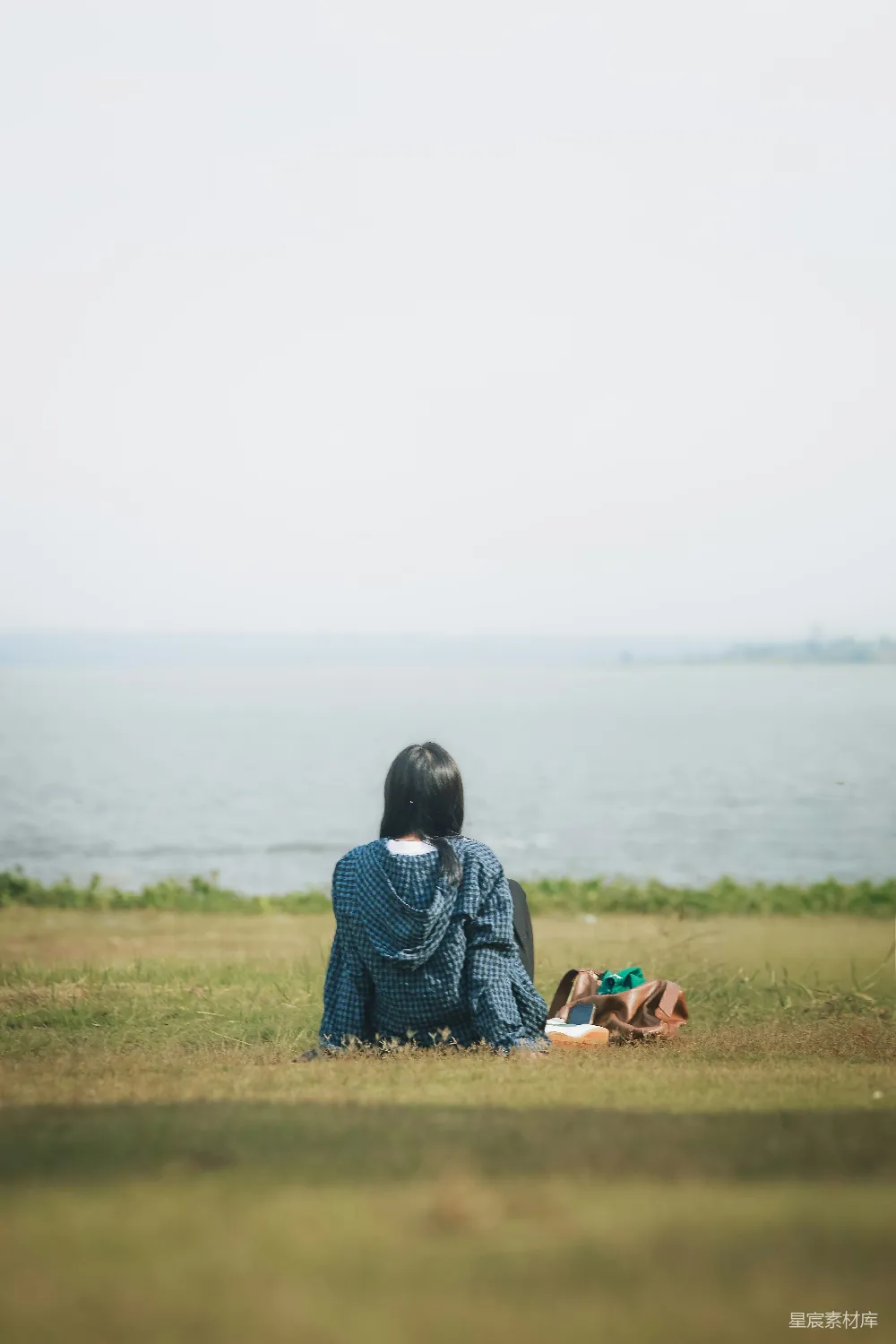 高清摄影  一个女人在阳光明媚的日子坐在水边。