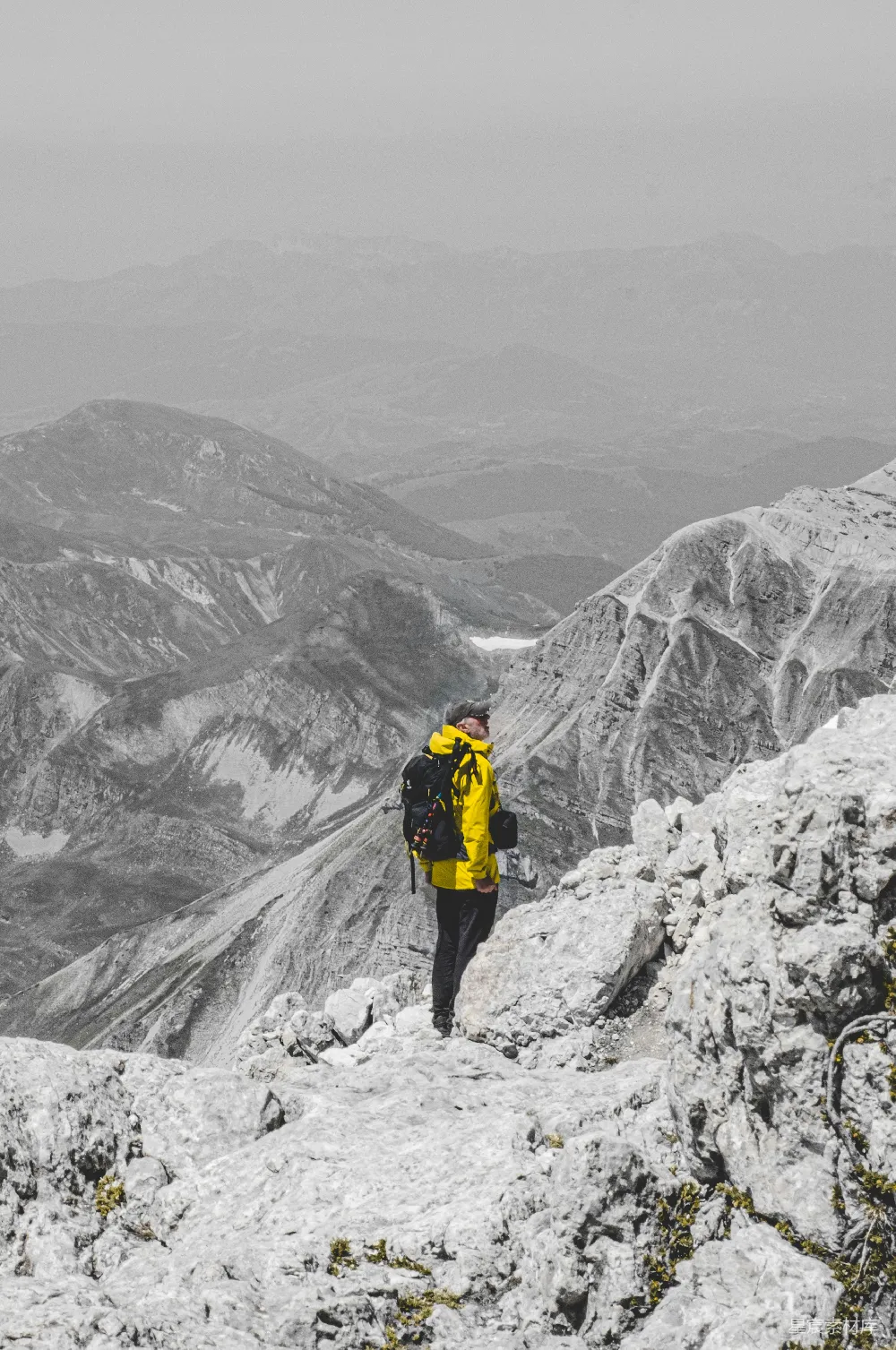 高清摄影  穿着黄色夹克和黑色裤子的人站在覆盖着积雪的山地上。
