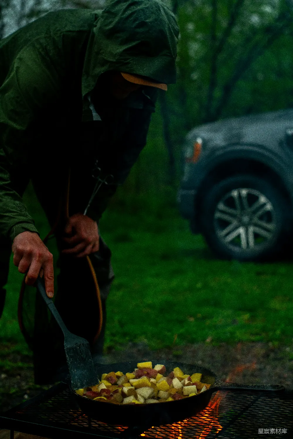 高清摄影  一个人正在雨中户外烹饪土豆。