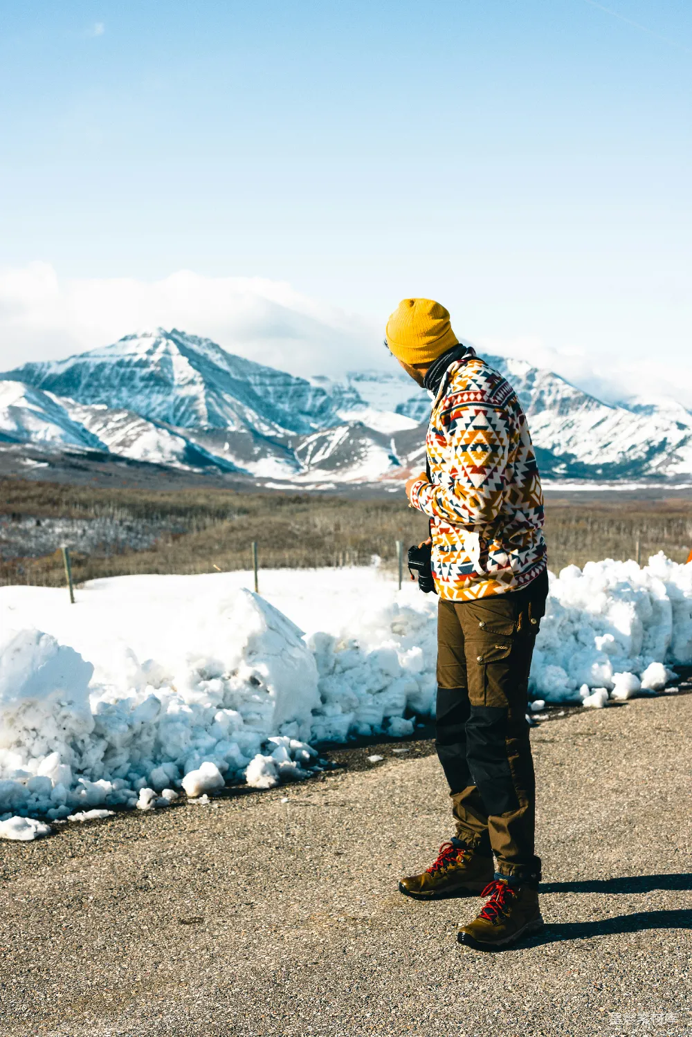 高清摄影  一个男人站在被雪覆盖的山脉前的公路上。