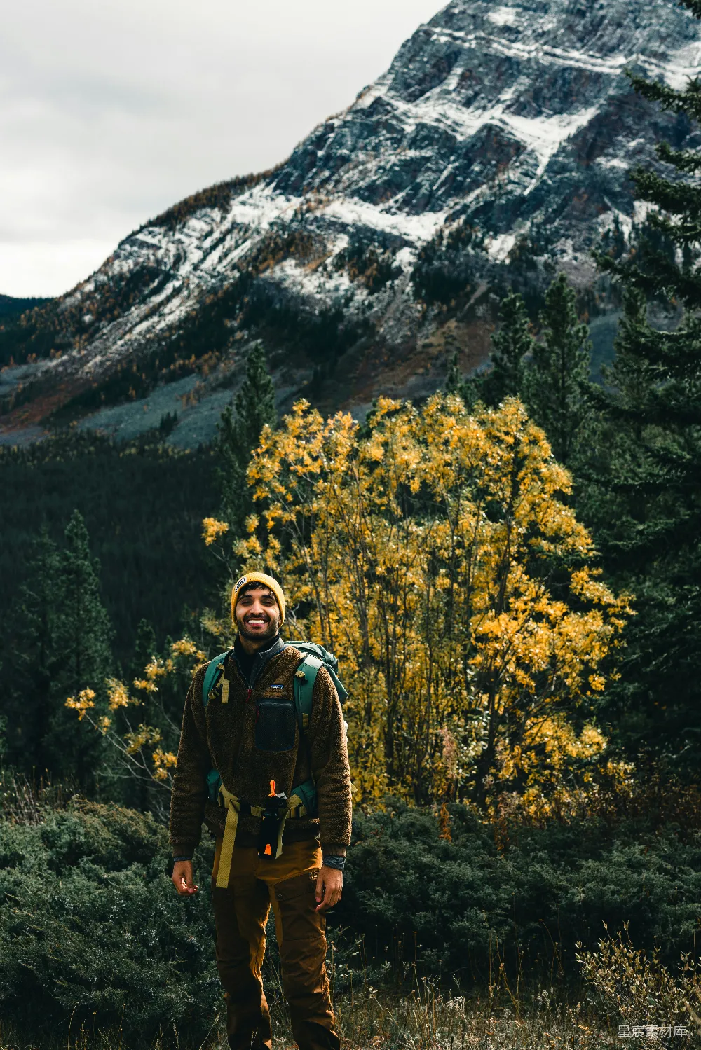 高清摄影  一个背着背包的男人站在一座山前。