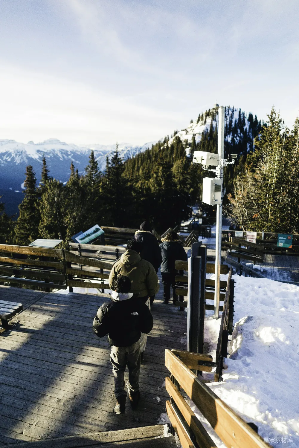 高清摄影  人们在被雪覆盖的山路行走，两旁是树木。