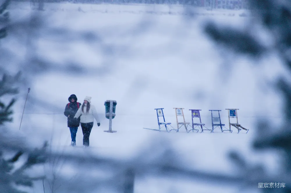 高清摄影  两个人从雪地里的雪橇旁走过。