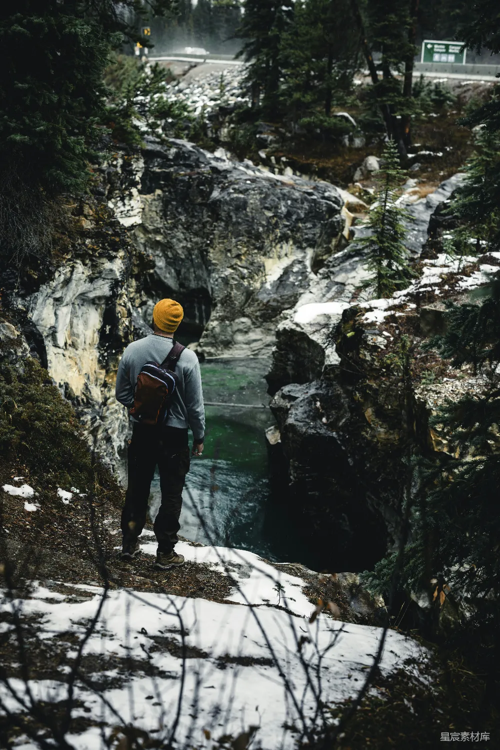 高清摄影  一个背着背包的男人站在一条雪地上。