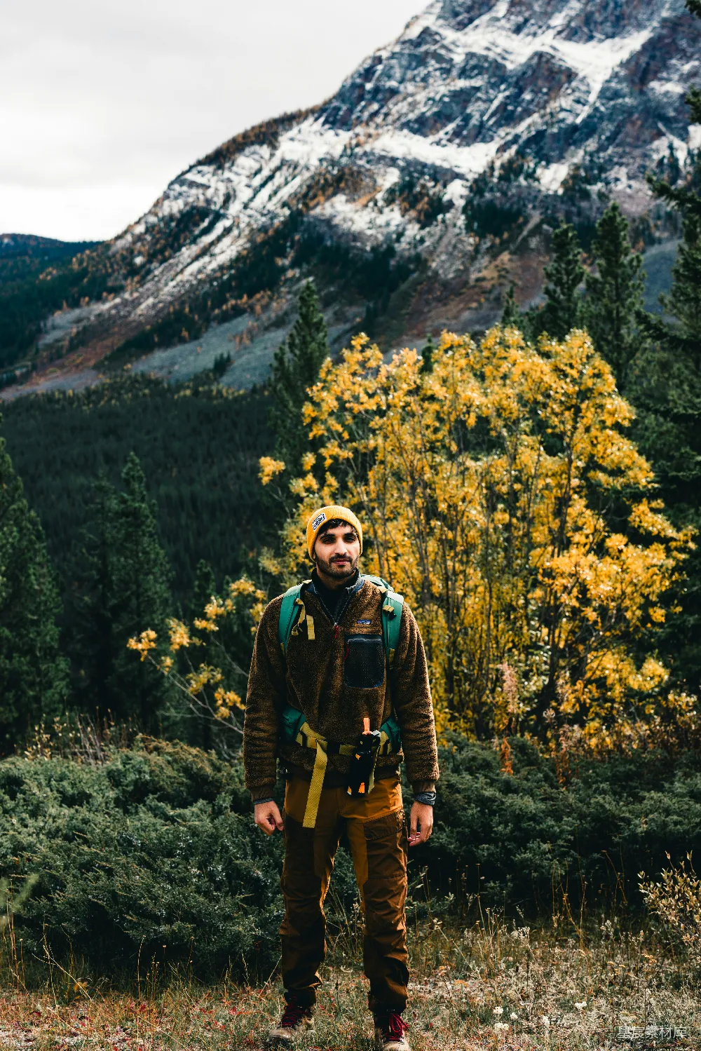 高清摄影  一个男人站在森林中央，背景是一座山。