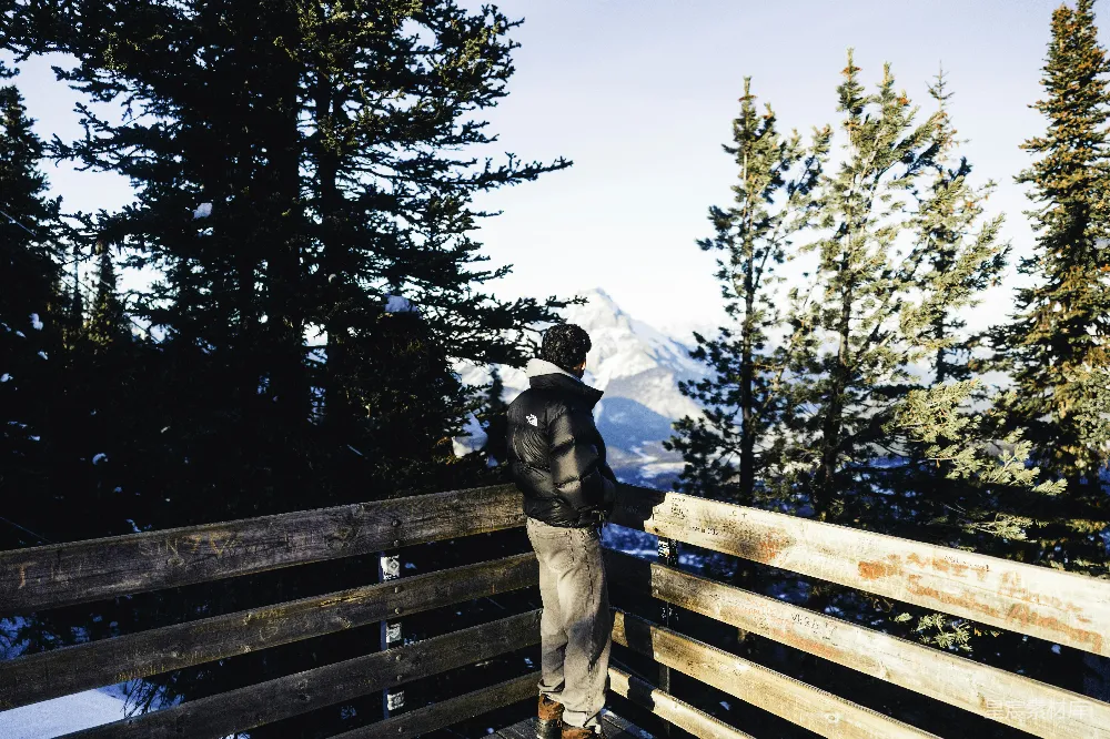 高清摄影  男人在木质阳台上望着雪山景色