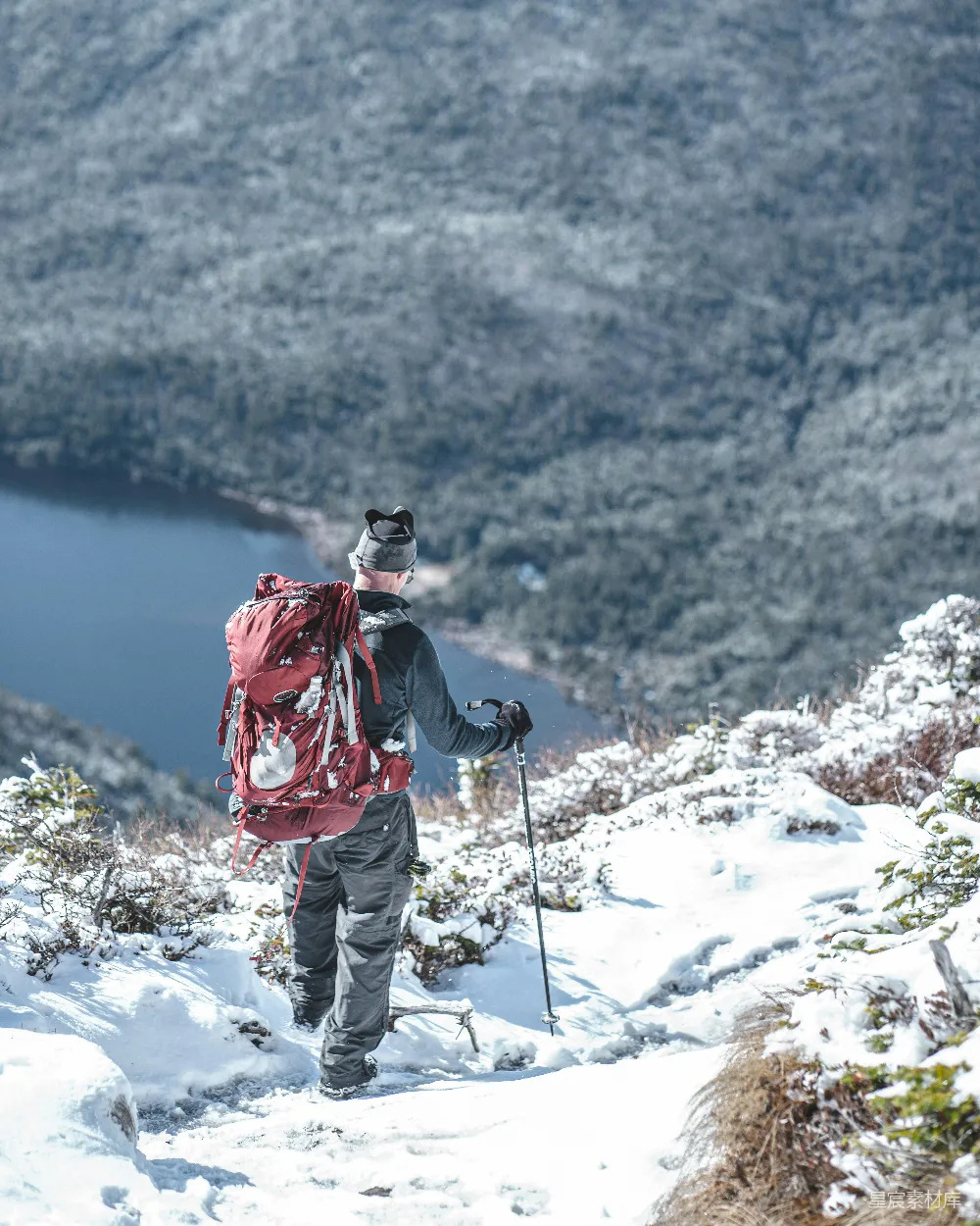 高清摄影  穿红色夹克和白色裤子的人站在白天被雪覆盖的山上。