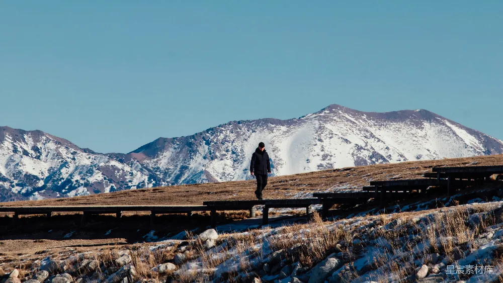高清摄影 壁纸 旅行 人物 一个人沿着木制小径走向雪山。