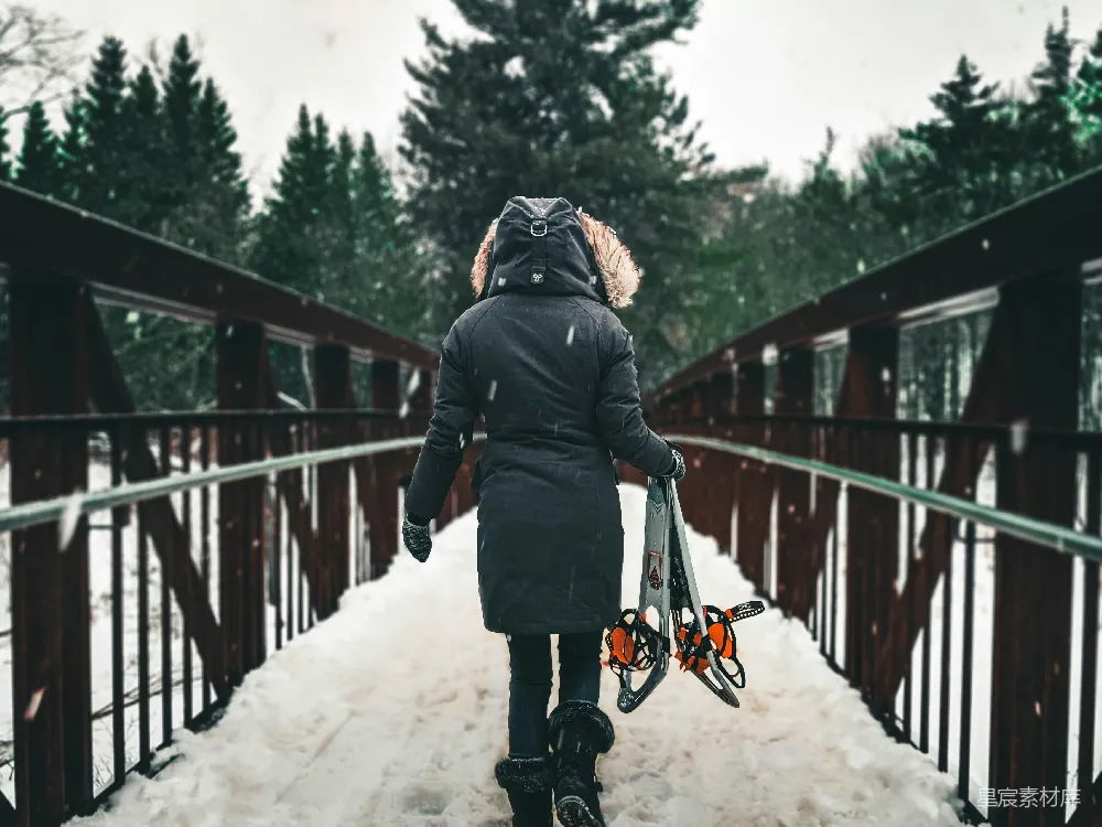 高清摄影  穿黑色夹克和黑色裤子的人在白天走在被雪覆盖的桥上。