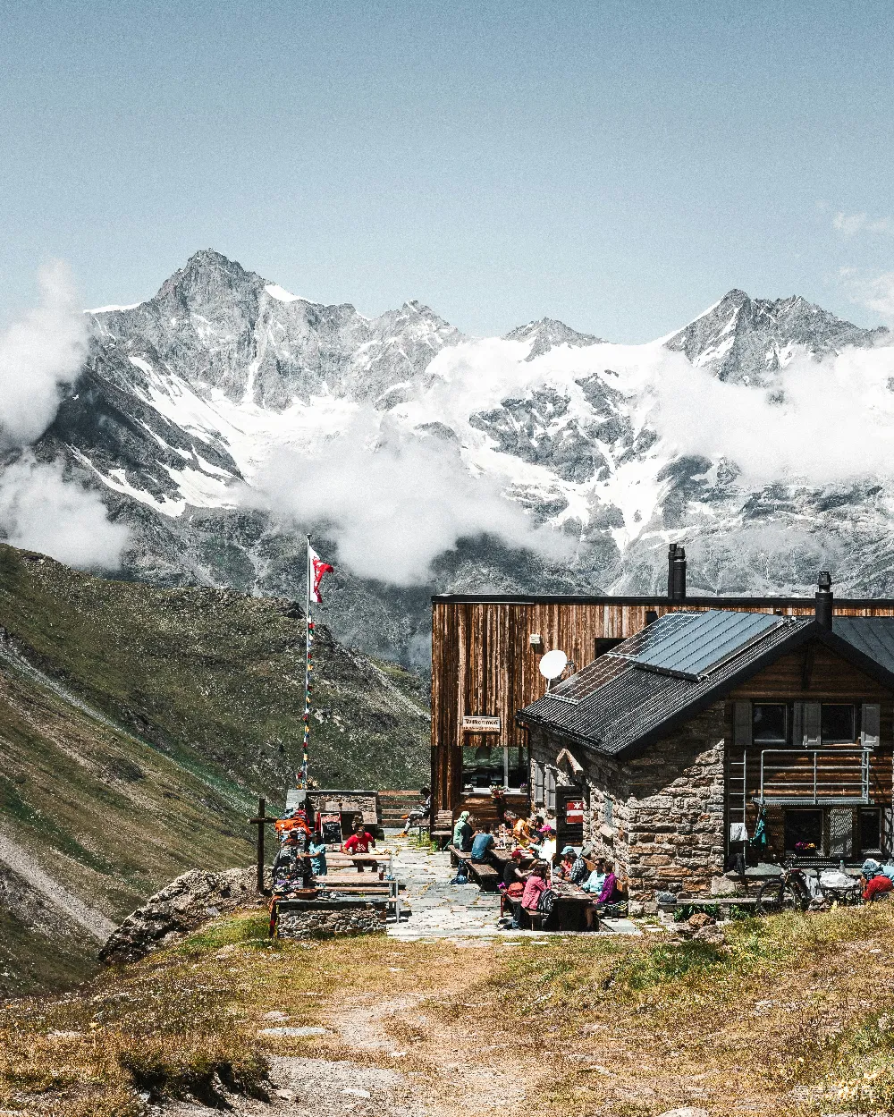 高清摄影  一群人坐在山顶小屋外面。