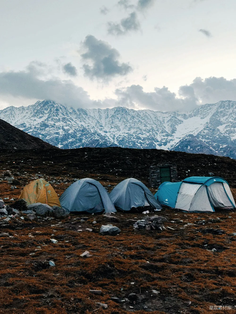 高清摄影  帐篷搭在岩石地面上，背景是雪山。
